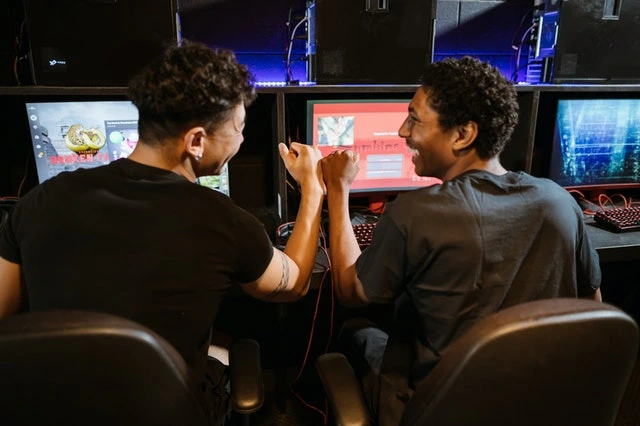 Two males fist bumping while playing computer